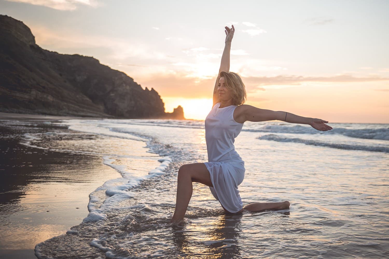 A picture of Nina Krüger doing a yoga pose at the beach.
