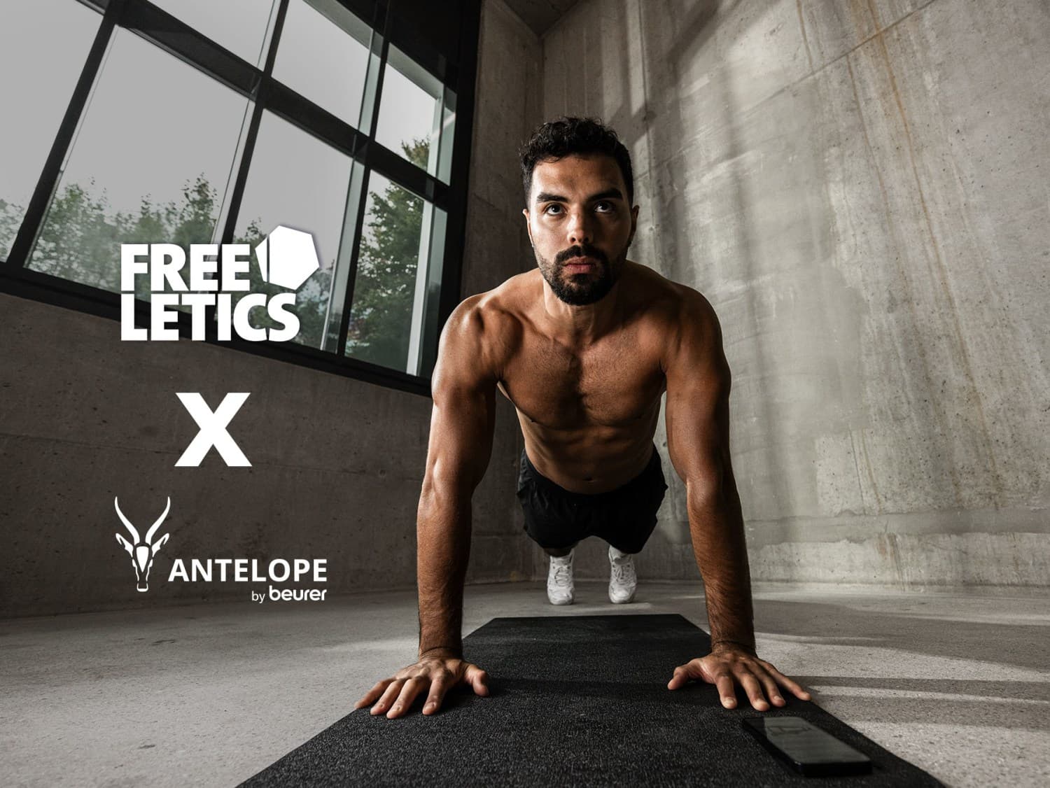 Freeletics x Antelope by Beurer: Muscular man doing a push-up on a black exercise mat